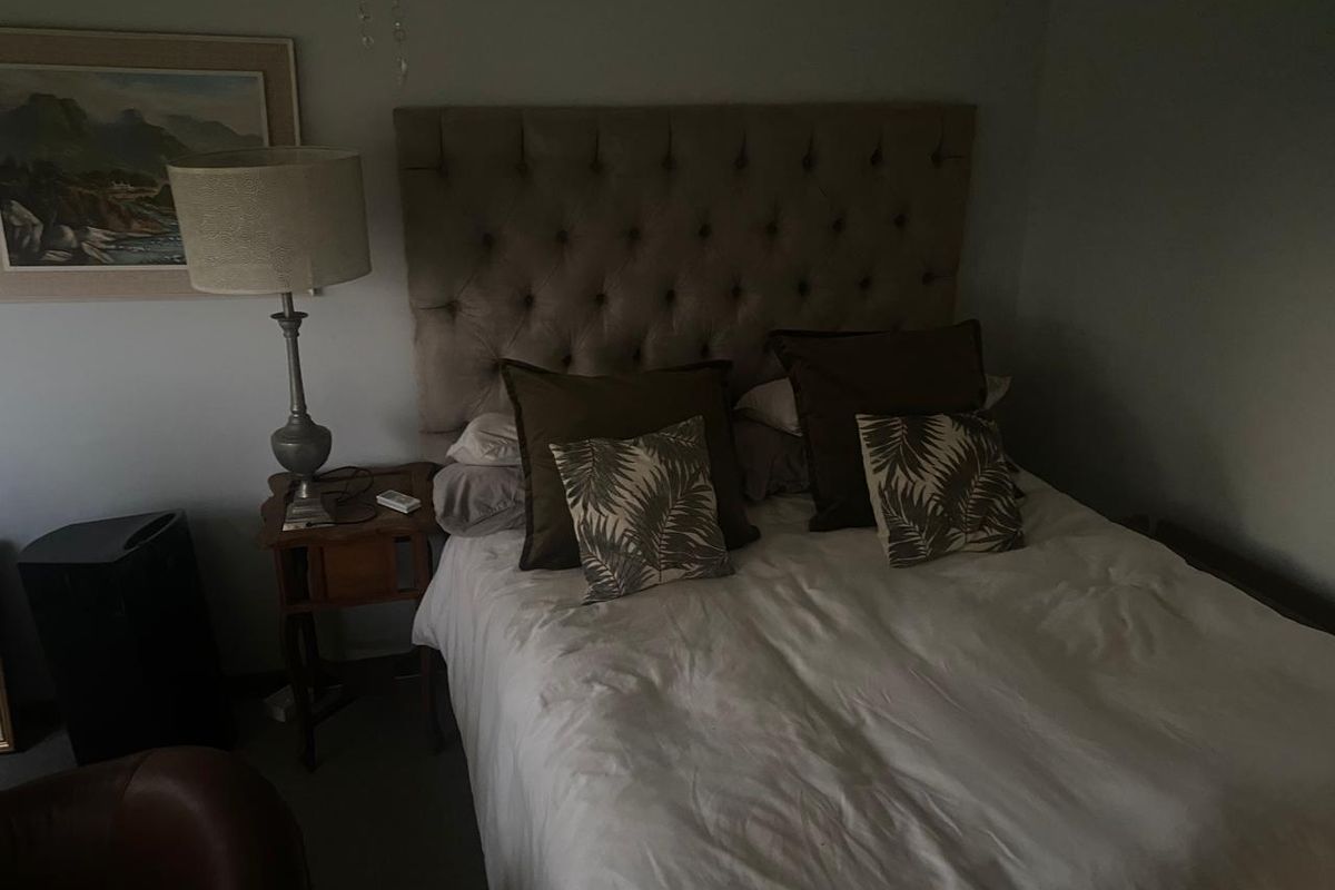 A bedroom featuring a tufted headboard, captured in low-light conditions.