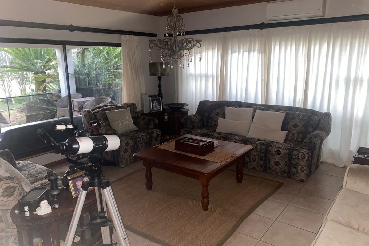 A comfortable living room featuring a timber ceiling, tiled flooring, and a split-system air conditioner, with large sliding doors providing access to the patio.