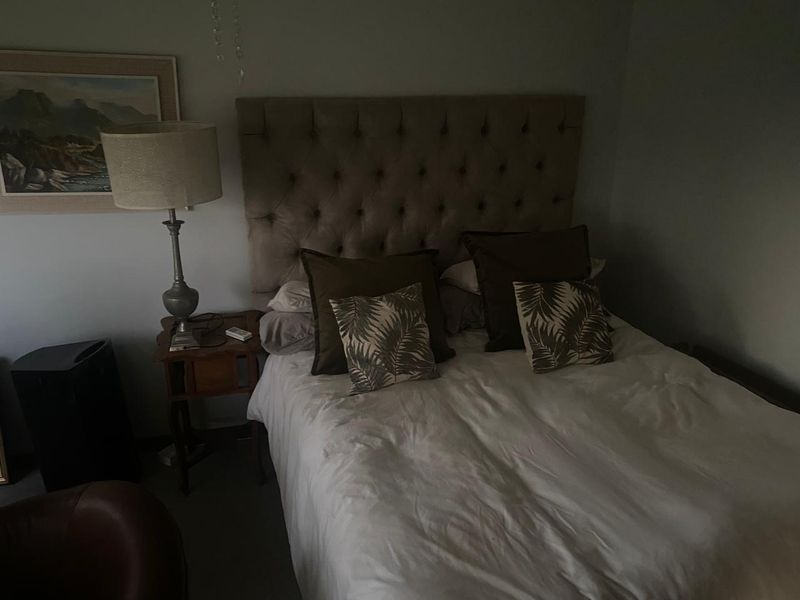 A bedroom featuring a tufted headboard, captured in low-light conditions.