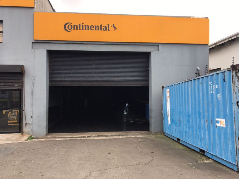 Commercial workshop frontage featuring a large roller shutter door and prominent signage, providing direct access to the interior workspace.