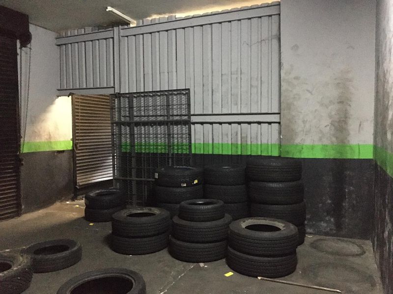 Commercial garage space featuring concrete flooring, metal wall cladding, and a secure roller shutter entrance.