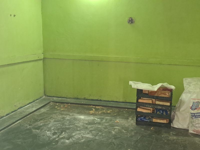 A utilitarian industrial space featuring concrete flooring and painted masonry walls, currently used for storage.