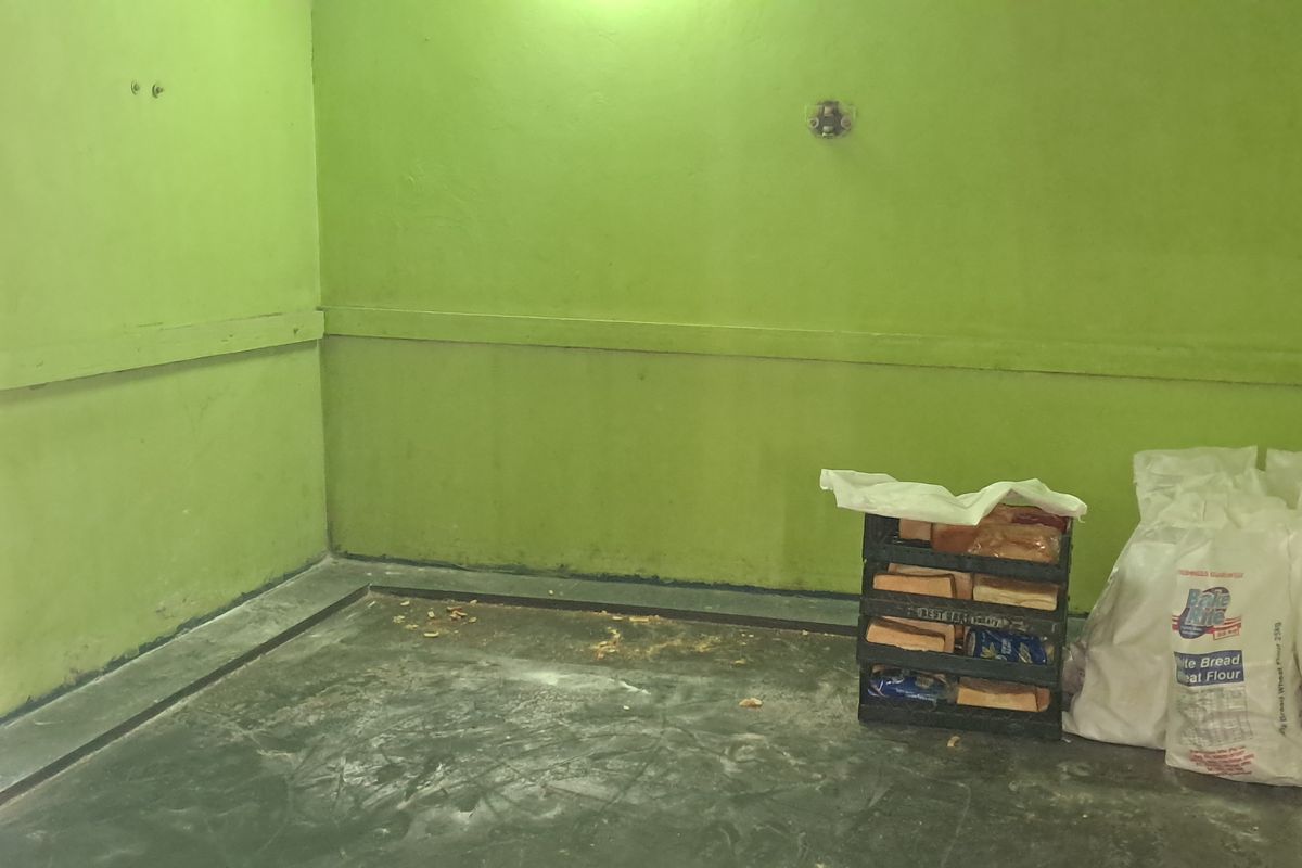 A utilitarian industrial space featuring concrete flooring and painted masonry walls, currently used for storage.