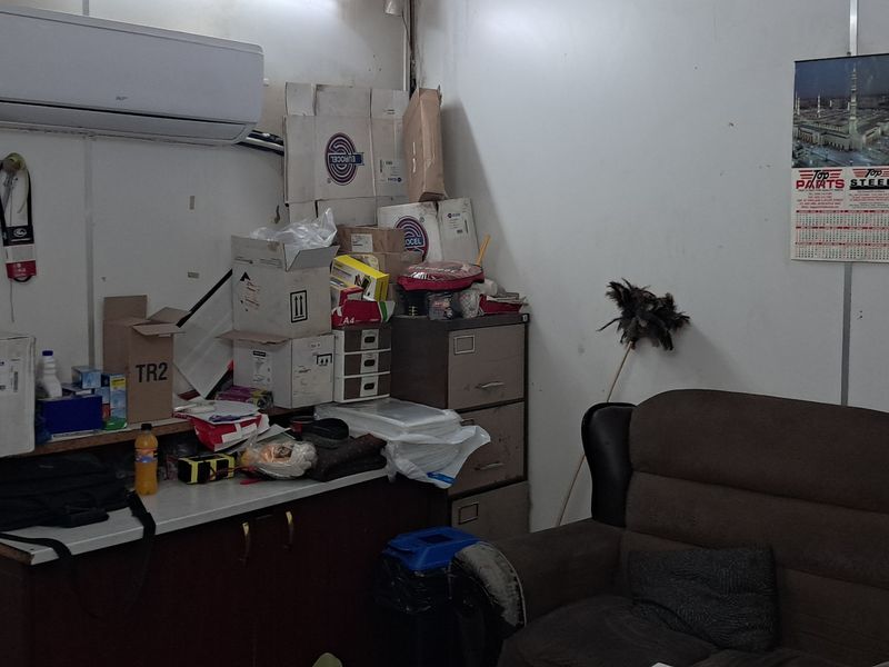 A functional office space featuring a wall-mounted split-system air conditioner and built-in storage cabinetry, suitable for administrative or industrial workspace use.
