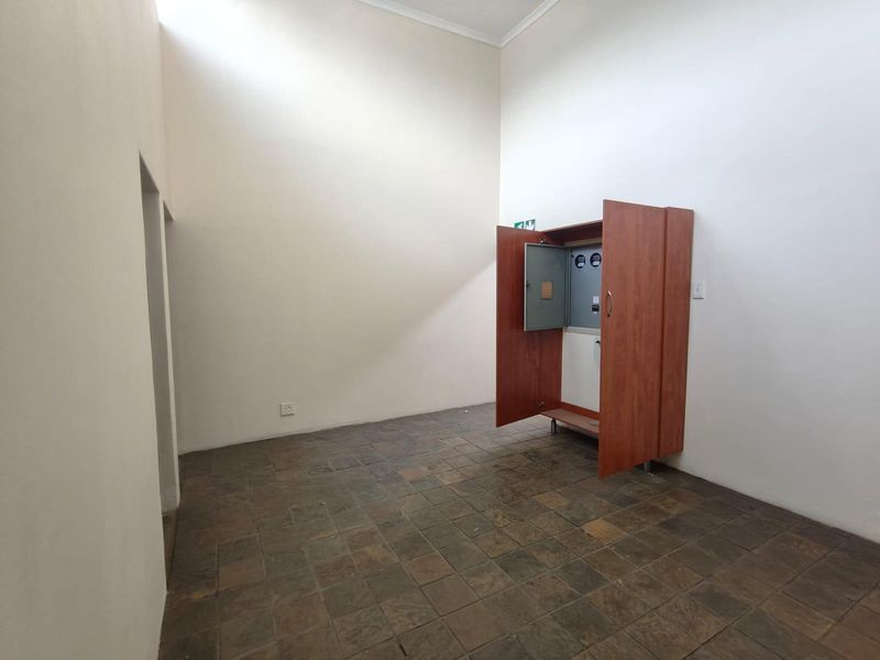 A functional utility space featuring high ceilings, tiled flooring, and a built-in cabinet housing the electrical distribution board.