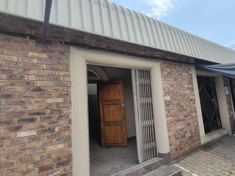 Front entrance of the office building featuring a face brick facade, corrugated metal roof, and a secure metal gate.