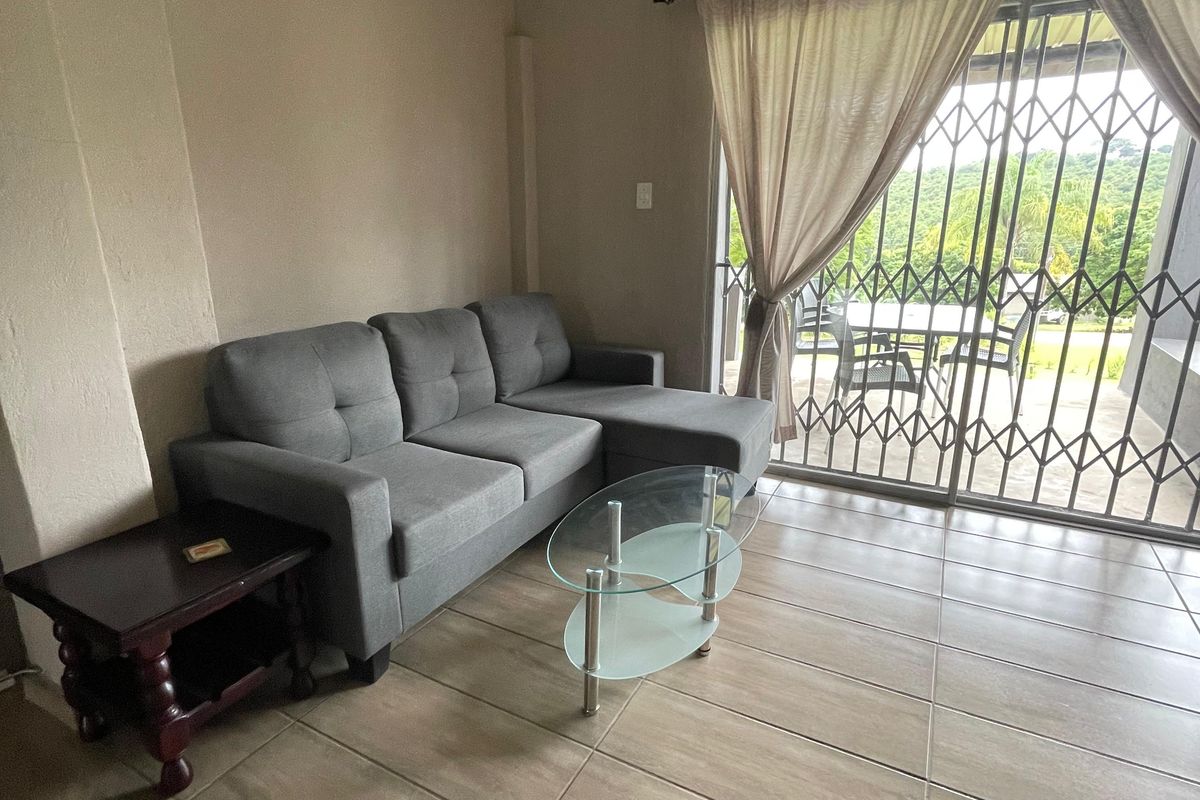 A living room featuring large format floor tiles, a sliding glass door with security gate, and direct access to an outdoor patio area.