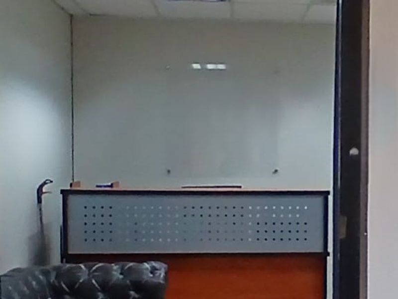 A functional office space featuring a built-in reception desk and a wall-mounted glass whiteboard, suitable for professional use.