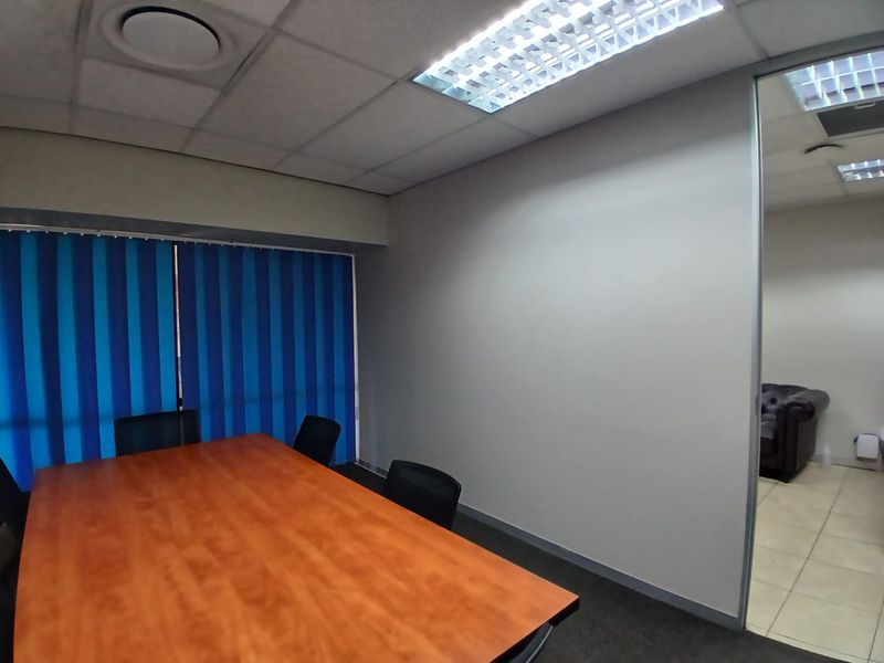 A functional office meeting room featuring a suspended ceiling, recessed lighting, and a glass partition wall, providing a professional workspace environment.