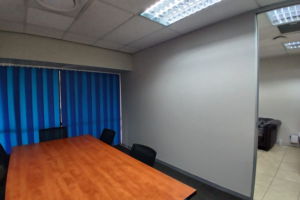 A functional office meeting room featuring a suspended ceiling, recessed lighting, and a glass partition wall, providing a professional workspace environment.