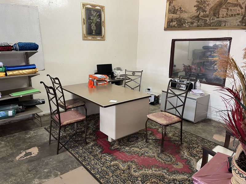 A functional office space featuring built-in shelving, an internal window, and exposed concrete flooring, suitable for a small business or administrative work area.