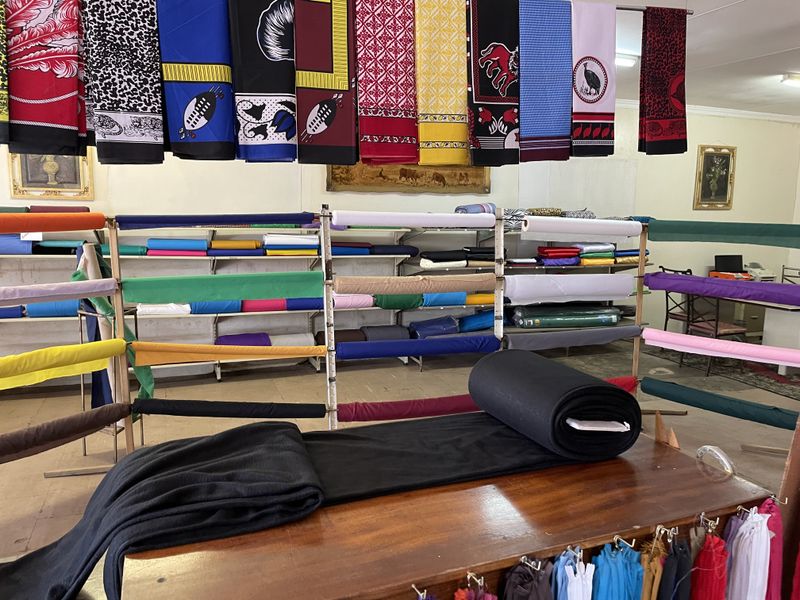 A retail space featuring extensive fabric display shelving and hanging textile displays, suitable for a textile or craft business.
