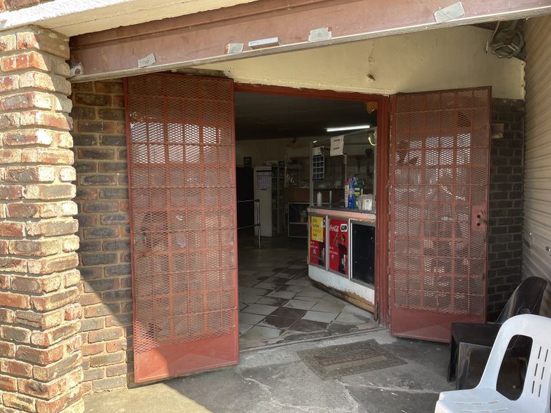 Entrance to a commercial space featuring a brick facade, security gates, and a service counter area with tiled flooring.