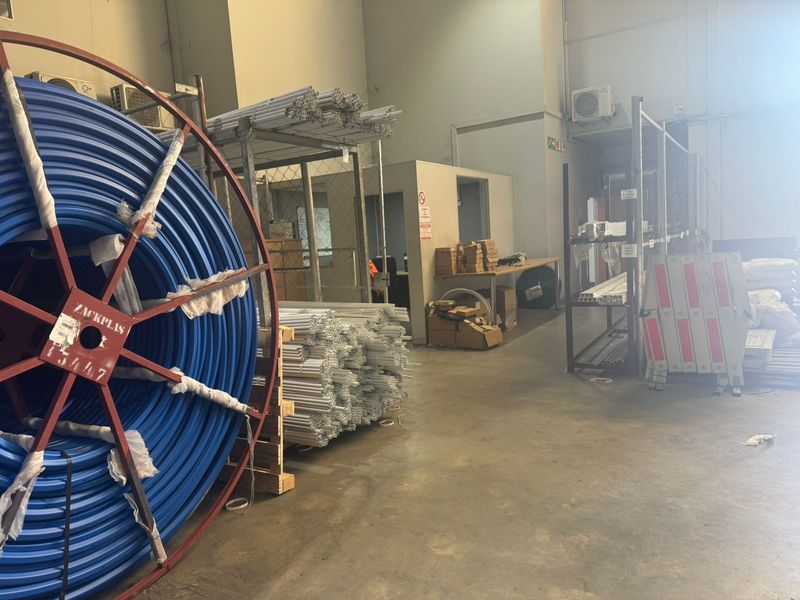 Industrial warehouse utility space featuring high ceilings, concrete flooring, and integrated office partitioning, suitable for storage or light industrial operations.