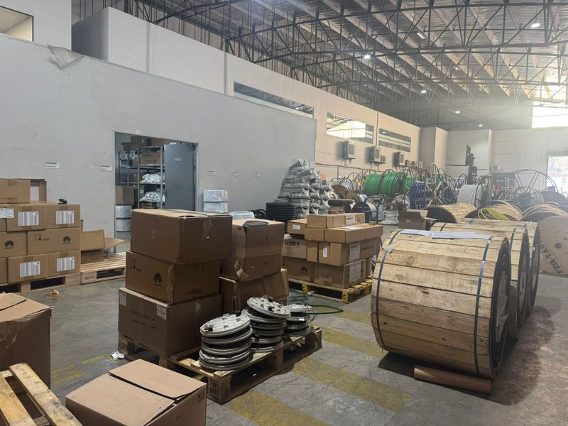 Spacious industrial warehouse facility featuring high ceilings with exposed steel trusses, concrete flooring, and integrated partitioned office space.