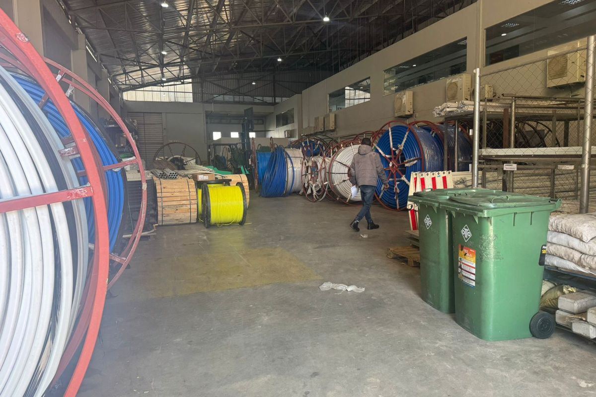 Spacious industrial warehouse featuring high ceilings with exposed steel trusses, concrete flooring, and mezzanine office access, suitable for storage or manufacturing operations.