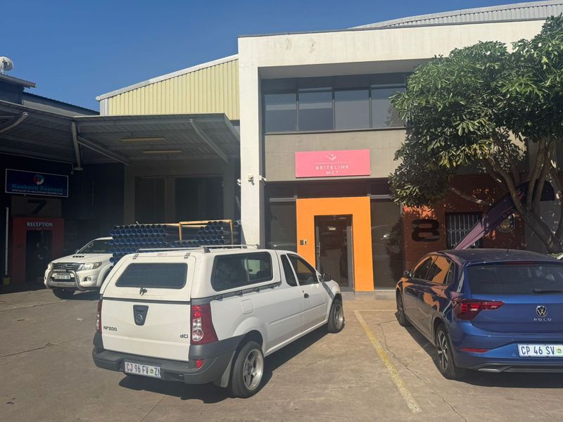Front facade of an industrial property featuring a main entrance, roller shutter door access, and paved parking area.