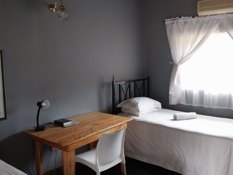 A bedroom featuring a high-pitched thatch ceiling, tiled flooring, and a wall-mounted air conditioning unit.