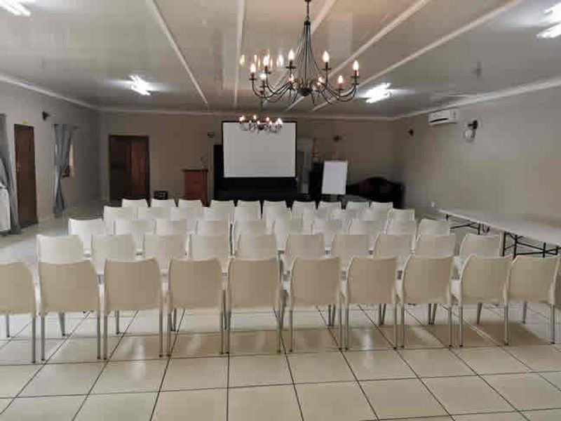 Spacious conference or event hall featuring tiled flooring, a projection screen, and integrated lighting, suitable for meetings or gatherings.