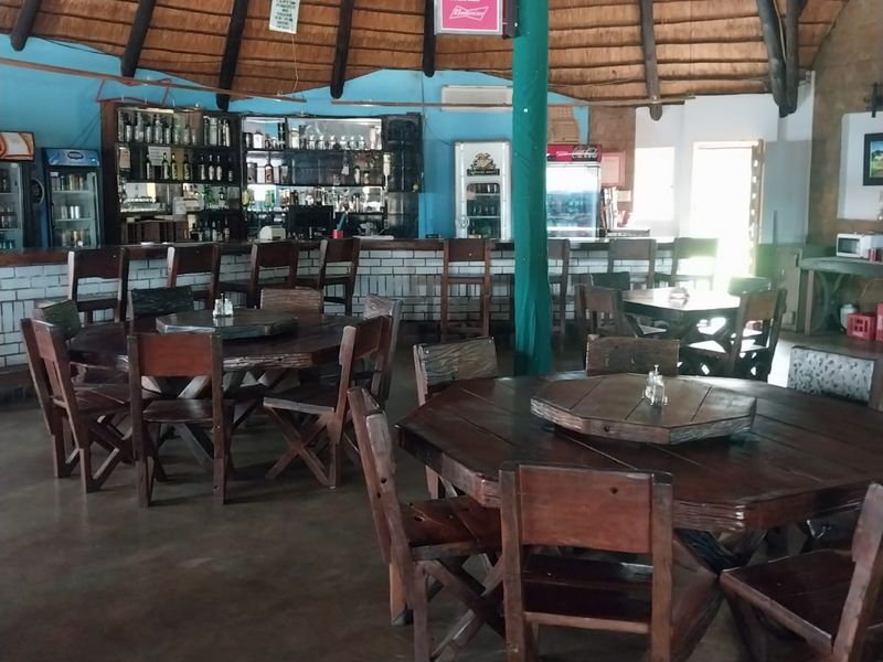 Spacious bar area featuring a traditional thatched roof with exposed timber rafters, a built-in bar counter, and concrete flooring.