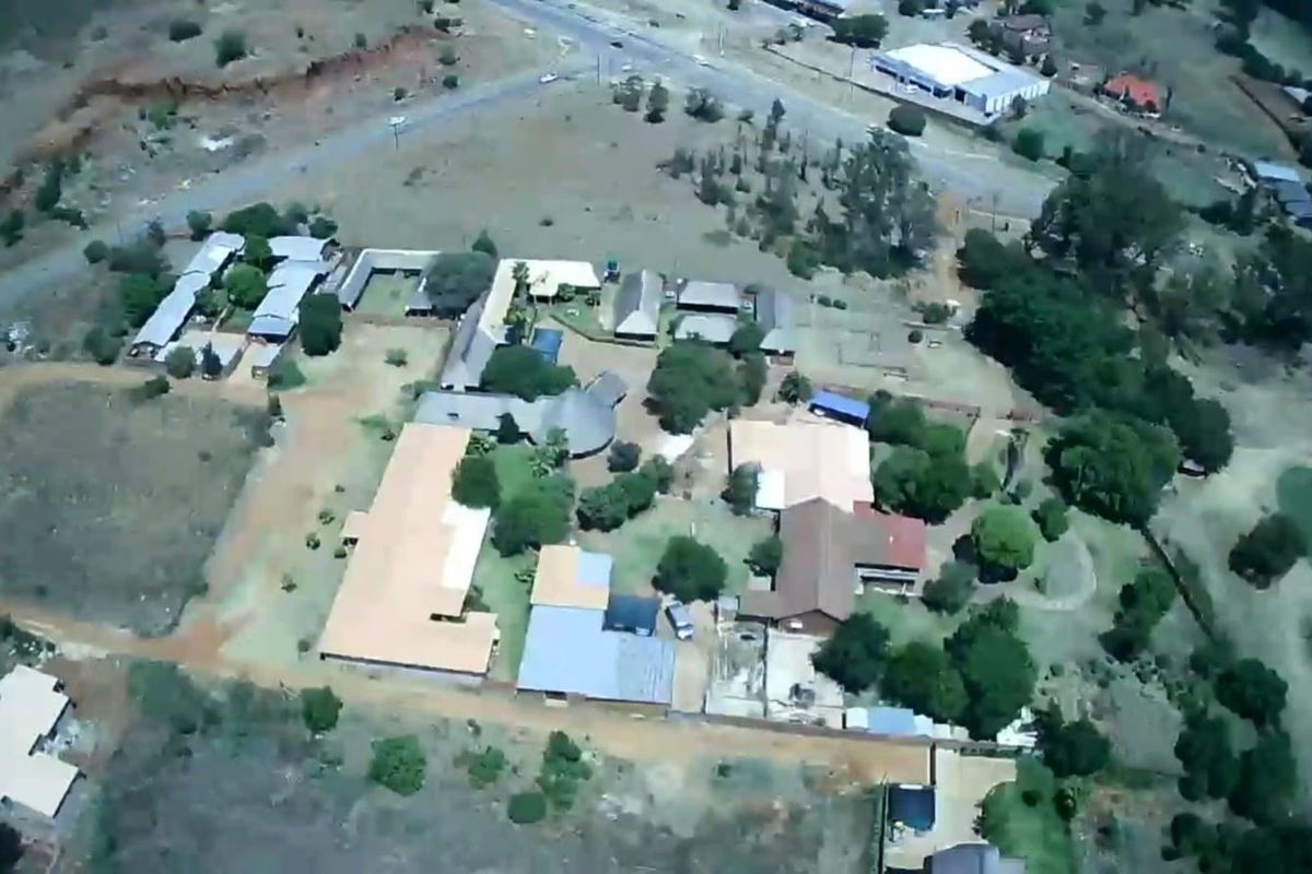 An aerial view of the guest house property showing multiple buildings, landscaped grounds, and surrounding access roads.