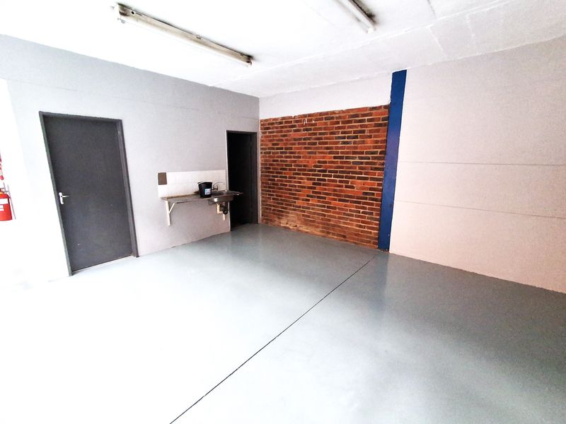 Industrial utility space featuring an exposed brick accent wall, durable epoxy flooring, and a functional wall-mounted stainless steel sink.