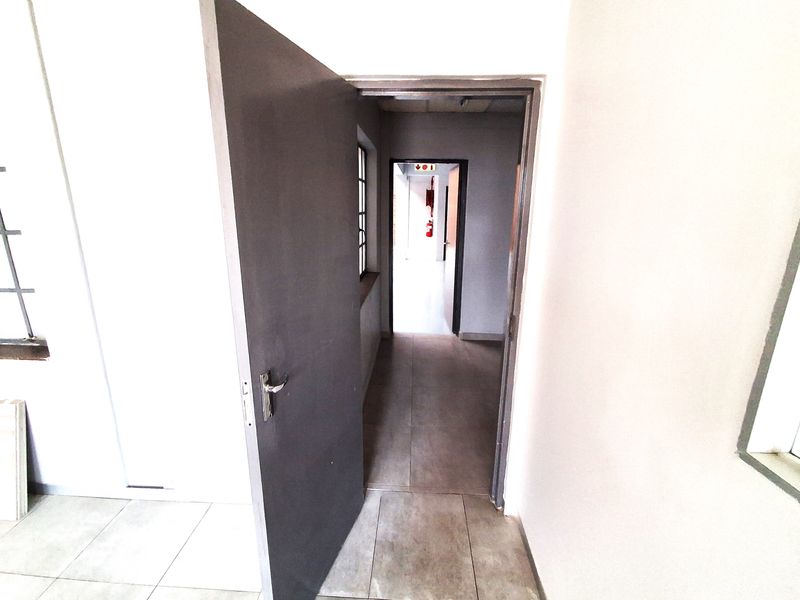 A functional industrial hallway featuring tiled flooring and clear access to adjoining office or utility spaces.