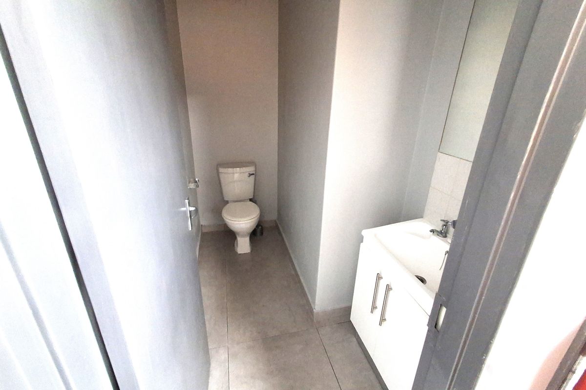 A compact, functional bathroom featuring a modern vanity unit with a washbasin and a standard toilet, finished with neutral floor tiles.