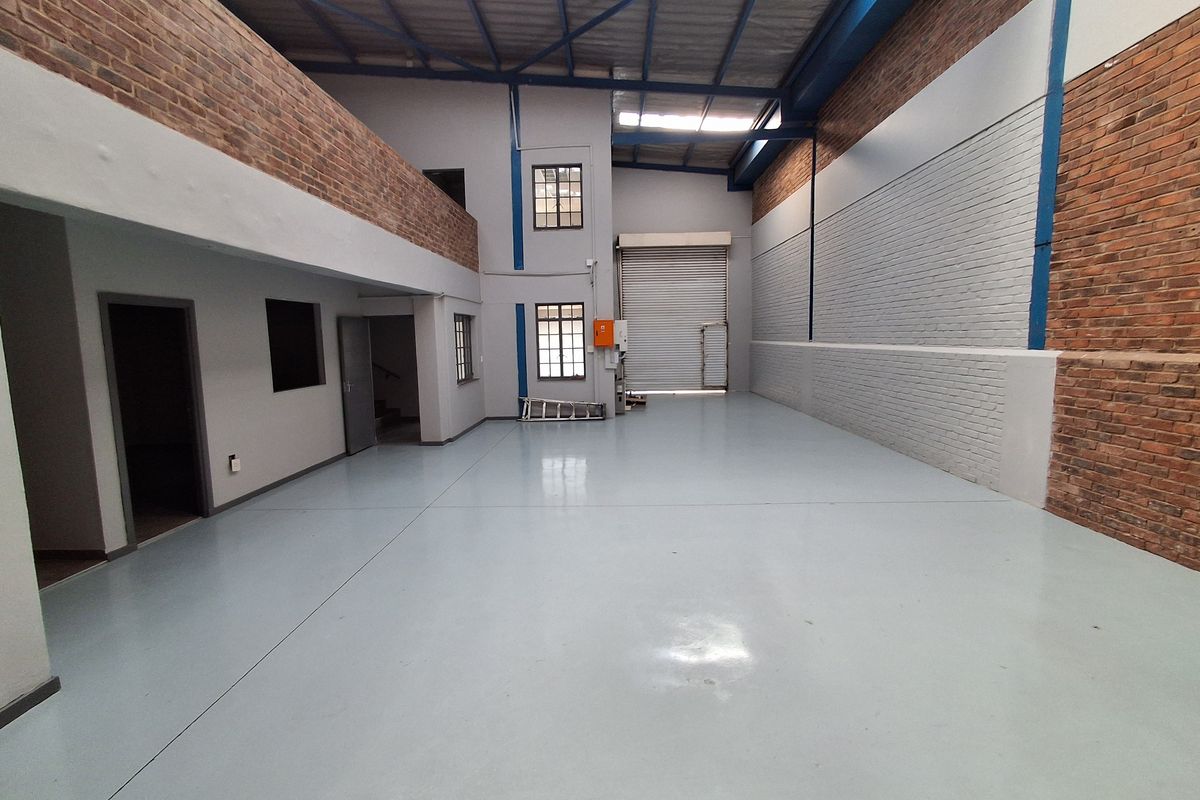 Spacious industrial warehouse unit featuring high ceilings, exposed brickwork, polished concrete flooring, and a large roller shutter door for easy access.