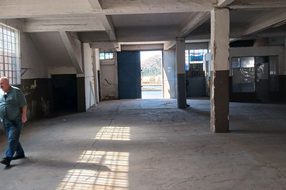 Spacious industrial utility area featuring concrete flooring, exposed structural beams, and large industrial doors, suitable for warehouse or workshop use.