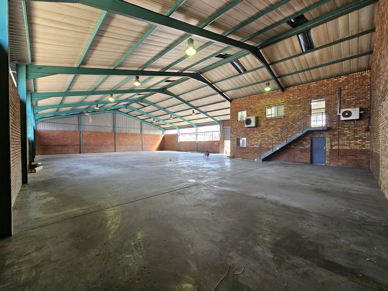 Spacious industrial warehouse featuring exposed brick walls, concrete flooring, high-clearance steel portal frame, and integrated air conditioning units.