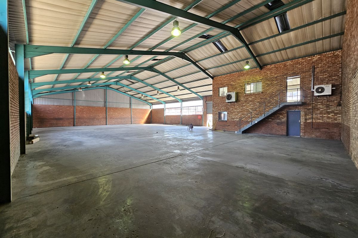 Spacious industrial warehouse featuring exposed brick walls, concrete flooring, high-clearance steel portal frame, and integrated air conditioning units.