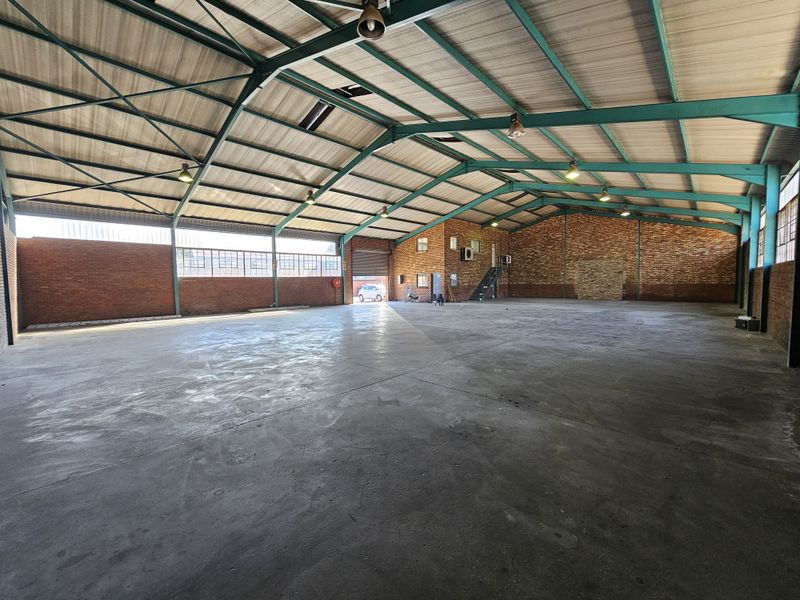 Spacious industrial warehouse featuring exposed steel trusses, concrete flooring, and brick walls, offering a versatile open-plan layout suitable for various commercial or storage operations.