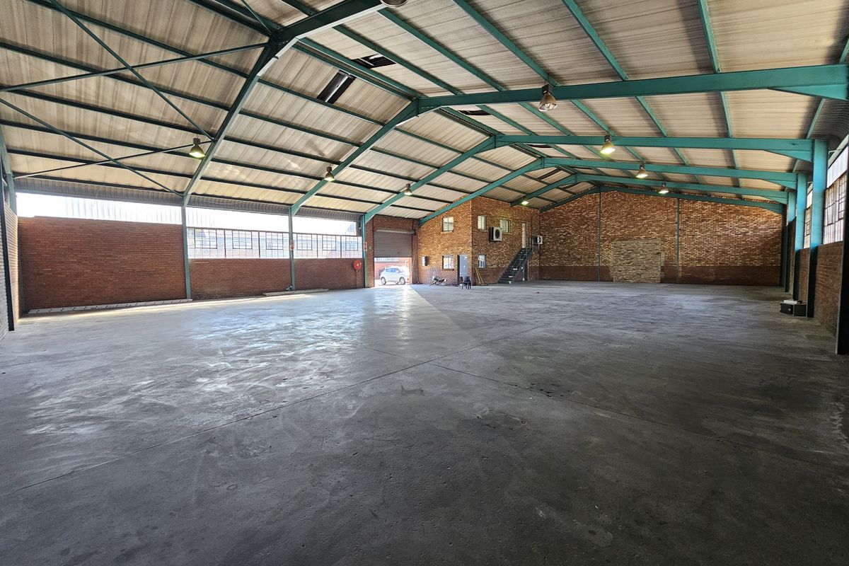 Spacious industrial warehouse featuring exposed steel trusses, concrete flooring, and brick walls, offering a versatile open-plan layout suitable for various commercial or storage operations.