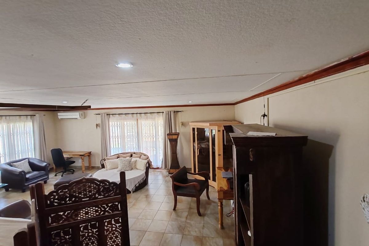 Spacious living area featuring tiled flooring, recessed lighting, and a split-system air conditioner, with large sliding doors providing access to the exterior.