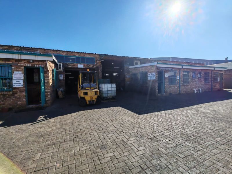 Industrial property exterior featuring a face brick facade, paved driveway, and secure access points with integrated office and warehouse entry areas.
