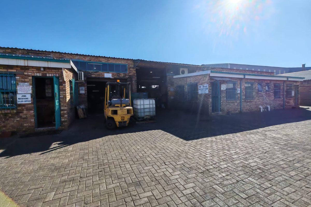 Industrial property exterior featuring a face brick facade, paved driveway, and secure access points with integrated office and warehouse entry areas.