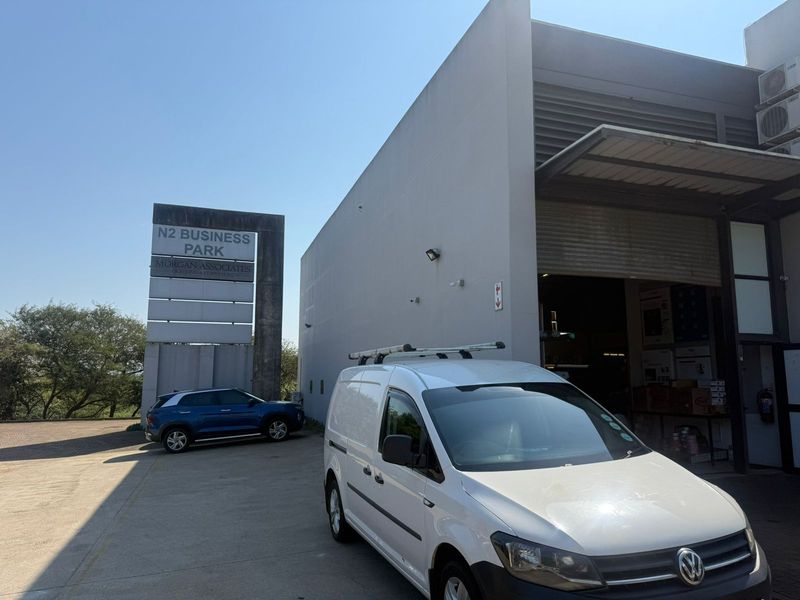 Front exterior view of an industrial unit in N2 Business Park, featuring a large roller shutter door and concrete driveway access.