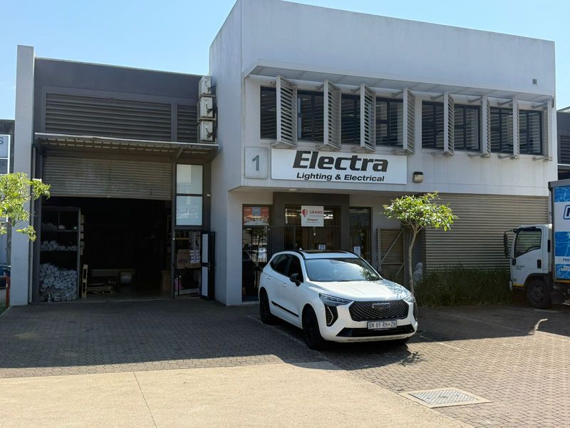 Front elevation of an industrial property featuring a roller shutter door, paved driveway, and professional signage for Electra Lighting & Electrical.