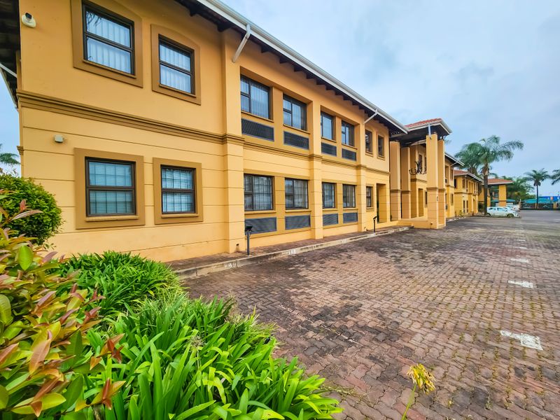 A multi-story office building exterior featuring a paved parking area, yellow facade, and multiple casement windows.