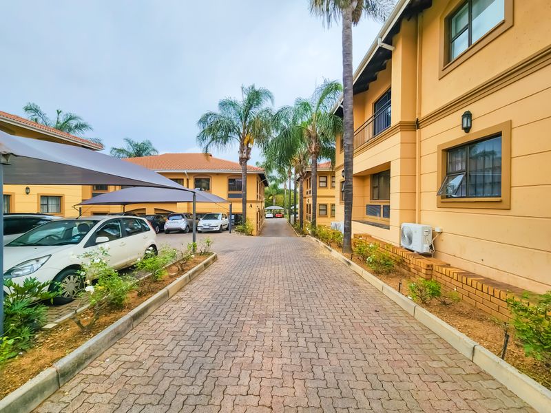 Exterior view of an office complex featuring a paved driveway, covered parking bays, and well-maintained building facades with established landscaping.