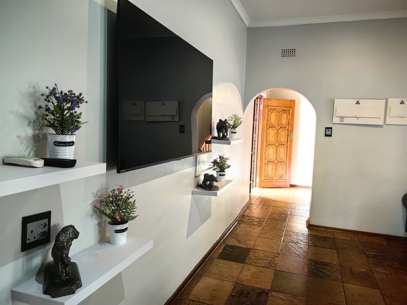 A well-maintained hallway featuring stone tile flooring, an arched doorway leading to an exterior entrance, and built-in wall shelving.