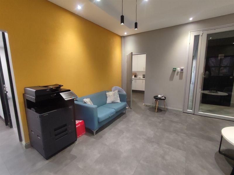 Modern office space featuring tiled flooring, recessed and pendant lighting, and a glass panel door leading to an adjacent area.