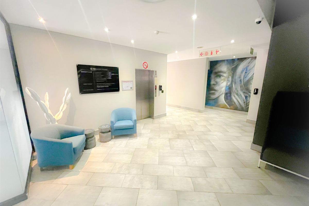 Modern office building lobby featuring tiled flooring, recessed lighting, a central elevator, and professional building directory signage.