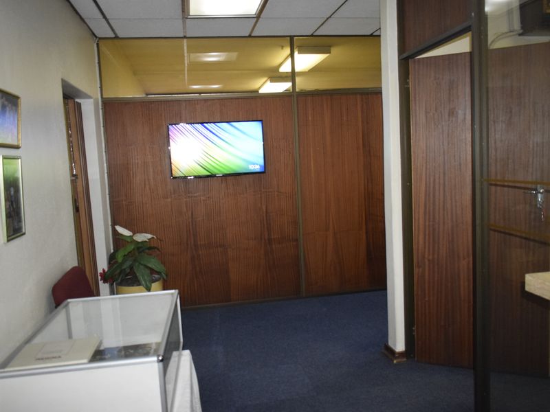 Office space featuring wood veneer partition walls, suspended ceiling with fluorescent lighting, and blue carpet flooring.