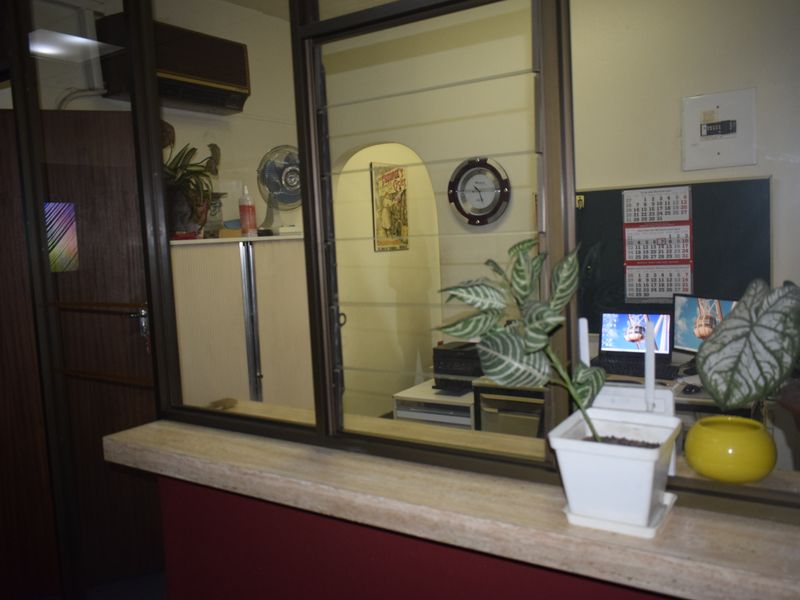 An office reception area featuring a service counter with a glass partition, providing a functional workspace with an integrated air conditioning unit.