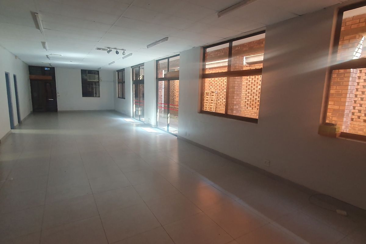 Spacious open-plan retail area featuring tiled flooring, suspended ceilings, and large windows providing ample natural light.