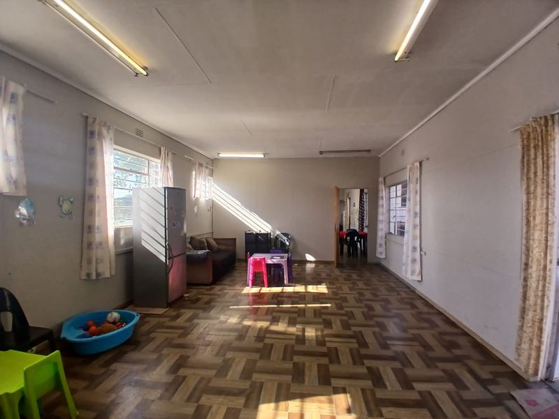 Spacious open-plan commercial area featuring parquet flooring, fluorescent lighting, and large windows, suitable for a variety of business or office configurations.