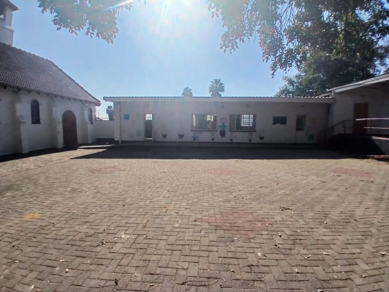 A spacious paved courtyard area situated between commercial building structures, featuring a mix of traditional and flat-roofed architectural styles.