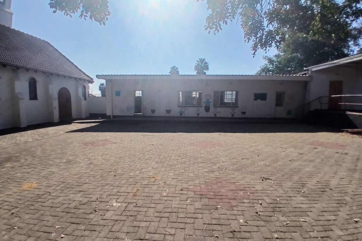 A spacious paved courtyard area situated between commercial building structures, featuring a mix of traditional and flat-roofed architectural styles.